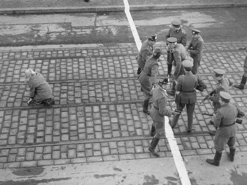 Упавшая на колени девушка, которой удалось перебежать границу между Восточным и Западным Берлином